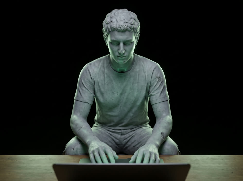 Estátua de mármore de frente, mãos no teclado de um notebook aceso